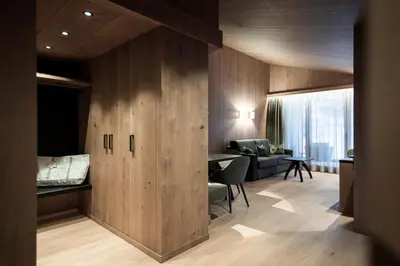 a room with a wooden wall with a living room at Hotel Cappella in Colfosco