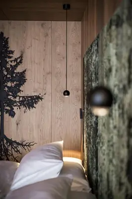 a bedroom with a bed with a tree on the wall at Hotel Cappella in Colfosco