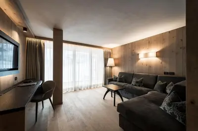 a living room with a couch and a television at Hotel Cappella in Colfosco