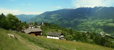 a village on a hill with mountains in the background at Agriturismo Gfaderhof in Bressanone