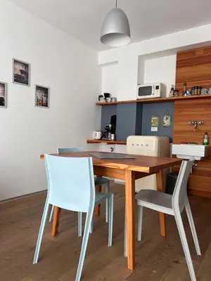 a kitchen with a wooden table and white chairs at M-Loft merangardenvilla in Merano