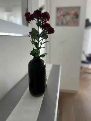 a black vase with purple flowers sitting on a table at M-Loft merangardenvilla in Merano
