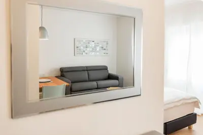 a mirror hanging on a wall in a room with a couch at M-Loft merangardenvilla in Merano