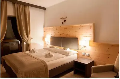 a bedroom with a large bed and a chair at Hotel Alla Rocca in Varena