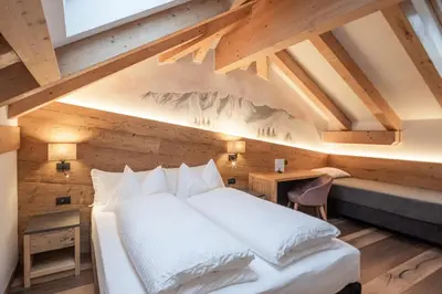 a bedroom with a white bed in a wooden wall at Hotel Bellavista in Cavalese
