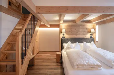 two beds in a room with a wooden staircase at Hotel Bellavista in Cavalese