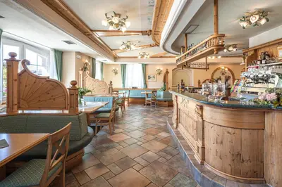 a restaurant with a bar and tables and chairs at Hotel Bellavista in Cavalese