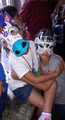 a young girl hugging a boy wearing a cow mask at Family Hotel Gran Baita in Pozza di Fassa