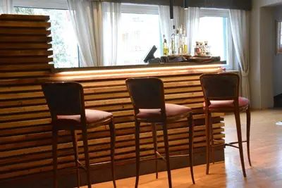 three chairs in front of a bar with a window at Family Hotel Gran Baita in Pozza di Fassa