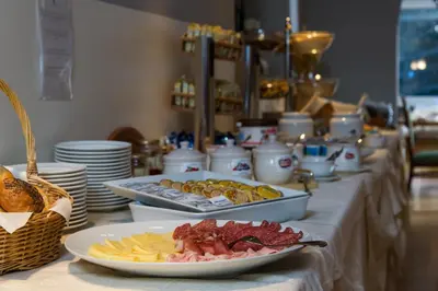 a buffet with plates of food on a table at Family Hotel Gran Baita in Pozza di Fassa