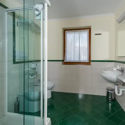 a bathroom with a glass shower and a sink at Family Hotel Gran Baita in Pozza di Fassa