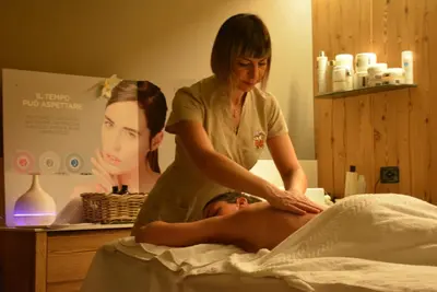 a woman giving a man a massage in a bed at Family Hotel Gran Baita in Pozza di Fassa