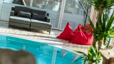 a living room with a couch and red pillows next to a pool at Hotel Post - Olang in Valdaora
