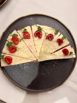 a pizza on a black plate with strawberries on it at Hotel Post - Olang in Valdaora