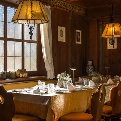 a dining room with a long table with chairs and lights at Hotel Post - Olang in Valdaora