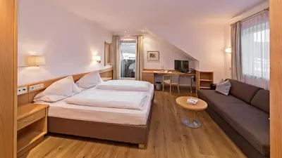 a hotel room with a bed and a couch at Hotel Post - Olang in Valdaora
