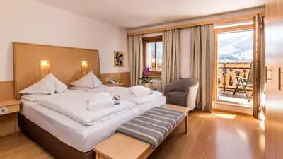 a hotel room with a large bed and a window at Hotel Post - Olang in Valdaora