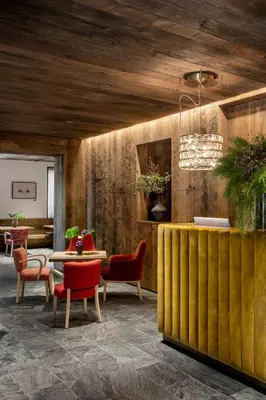 a lobby with red chairs and a table and a dining room at HOTEL de LEN in Cortina dʼAmpezzo