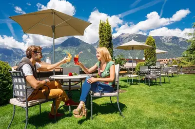 a man and woman sitting at a table with drinks at Hotel Walder in Schenna