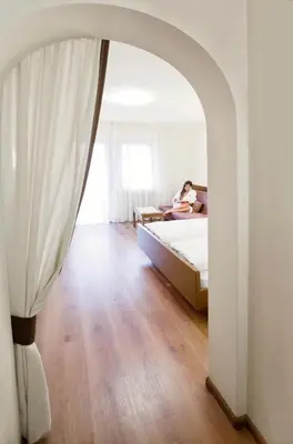 a woman is sitting on a bed in a bedroom at Hotel Walder in Schenna