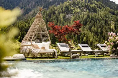 a group of lounge chairs sitting next to a pool at Alpin Garden Luxury Maison & SPA - Adults Retreat in Ortisei