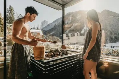a man and a woman cooking food on a grill at Alpin Garden Luxury Maison & SPA - Adults Retreat in Ortisei