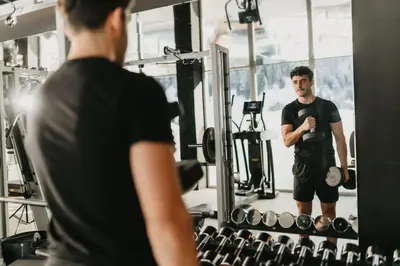 a man in a gym looking at his reflection in a mirror at Alpin Garden Luxury Maison & SPA - Adults Retreat in Ortisei