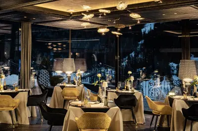 a restaurant with white tables and chairs and a large window at Alpin Garden Luxury Maison & SPA - Adults Retreat in Ortisei