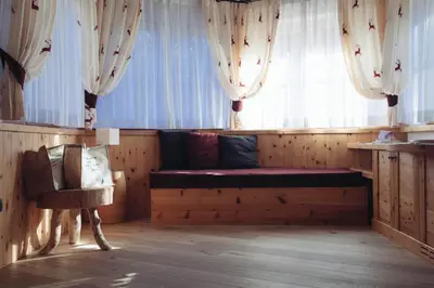 a room with a bench and a window with curtains at Pineta Nature Resort - Wellness & SPA in Coredo