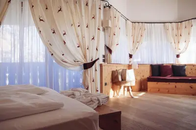 a bedroom with a bed and curtains and a couch at Pineta Nature Resort - Wellness & SPA in Coredo