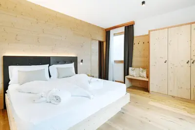 a bedroom with a large white bed with white sheets at Pineta Nature Resort - Wellness & SPA in Coredo