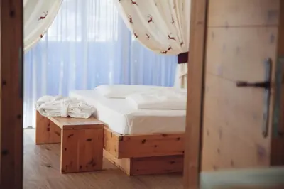 a bedroom with a bed and a table and a window at Pineta Nature Resort - Wellness & SPA in Coredo