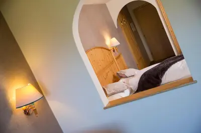 a mirror in a room with a bed and a lamp at Olympic SPA Hotel - Adults Only in Vigo di Fassa