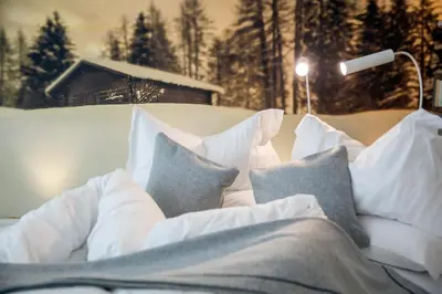 a bed with white pillows and a lamp at Olympic SPA Hotel - Adults Only in Vigo di Fassa