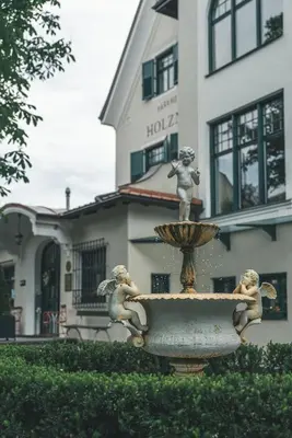 a fountain in front of a building with three statues on it at Parkhotel Holzner in Soprabolzano