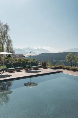 a swimming pool with chairs and a view of the mountains at Parkhotel Holzner in Soprabolzano