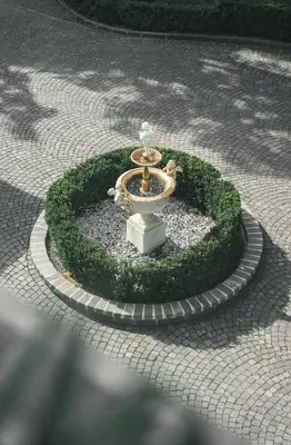 a fountain in the middle of a circle of grass at Parkhotel Holzner in Soprabolzano