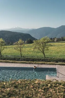 a person in a pool of water in a field at Parkhotel Holzner in Soprabolzano