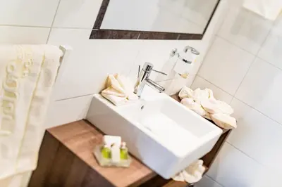a bathroom with a white sink and towels at Astor Hotel in Schenna