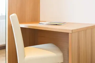 a desk with a white chair and a book on it at Astor Hotel in Schenna