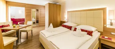 a hotel room with two beds and a table at Astor Hotel in Schenna