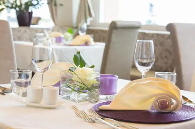a table with a hat and wine glasses on it at Astor Hotel in Schenna