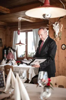 a man in a suit and tie holding a piece of paper at Hotel Ladinia in La Villa