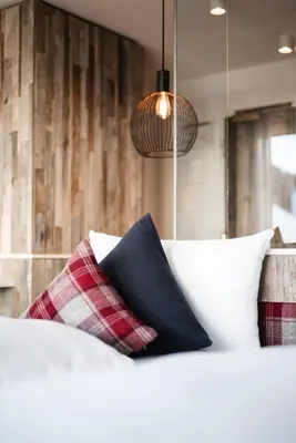 a bedroom with a bed with pillows and a lamp at Hotel Ladinia in La Villa