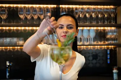 a woman is stirring a drink in a glass at Moar's Hotel in Valdaora