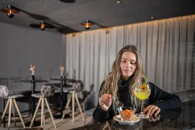 a woman sitting at a table with a drink at Moar's Hotel in Valdaora