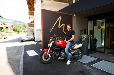 a man sitting on a motorcycle in front of a building at Moar's Hotel in Valdaora