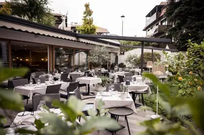 a restaurant with tables and chairs on a patio at Boutique Hotel Zum Rosenbaum in Nalles