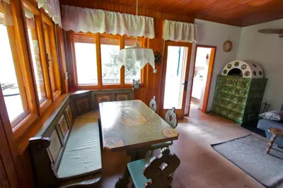 a living room with a table and some windows at Villa La Brisa in Predazzo