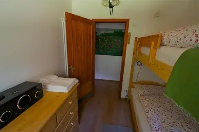 a small room with a bunk bed and a desk at Villa La Brisa in Predazzo